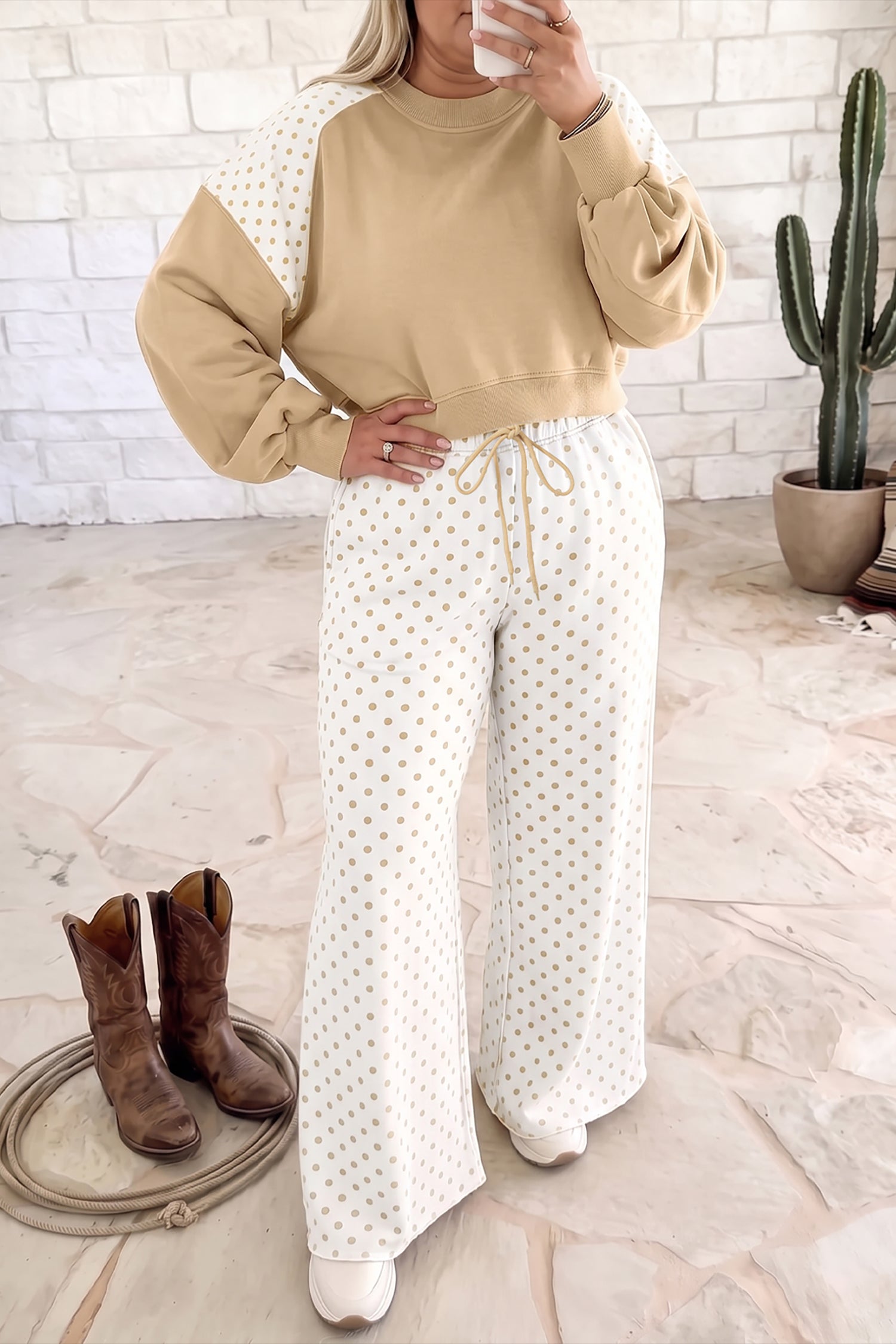 Woman wearing a beige and white polka dot lounge set with wide-leg pants and cowboy boots.