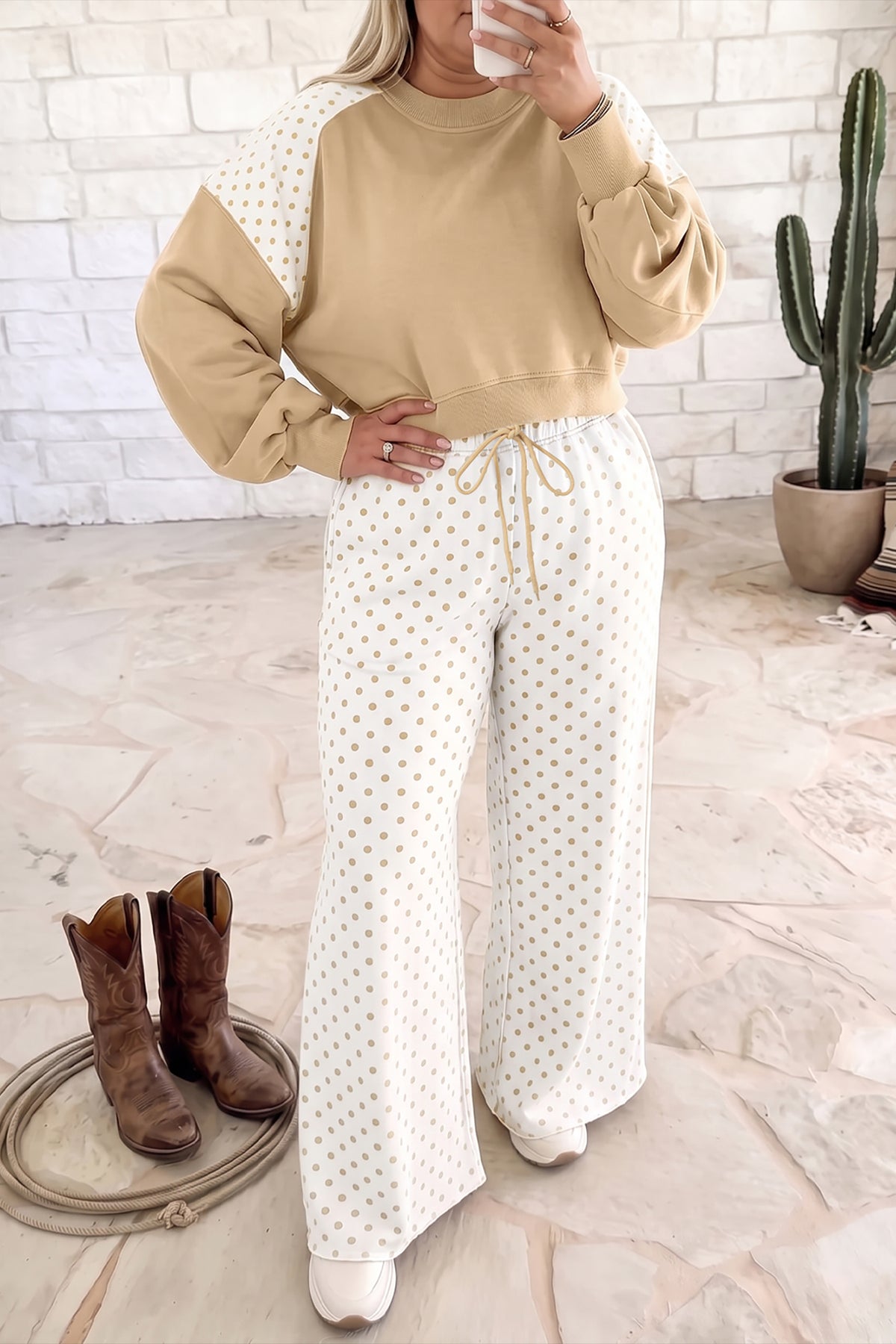 Woman wearing a beige and white polka dot lounge set with wide-leg pants and cowboy boots.
