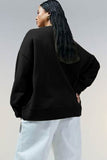 Woman shown from behind wearing a black oversized sweatshirt with white pants.