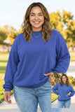 A woman wearing a royal blue crewneck sweatshirt and light wash jeans, standing outdoors on a paved path with trees in the background. A small inset image in the bottom right corner shows a front view of the sweatshirt.