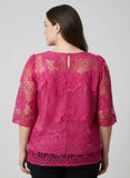 Woman wearing a pink lace top against a plain background