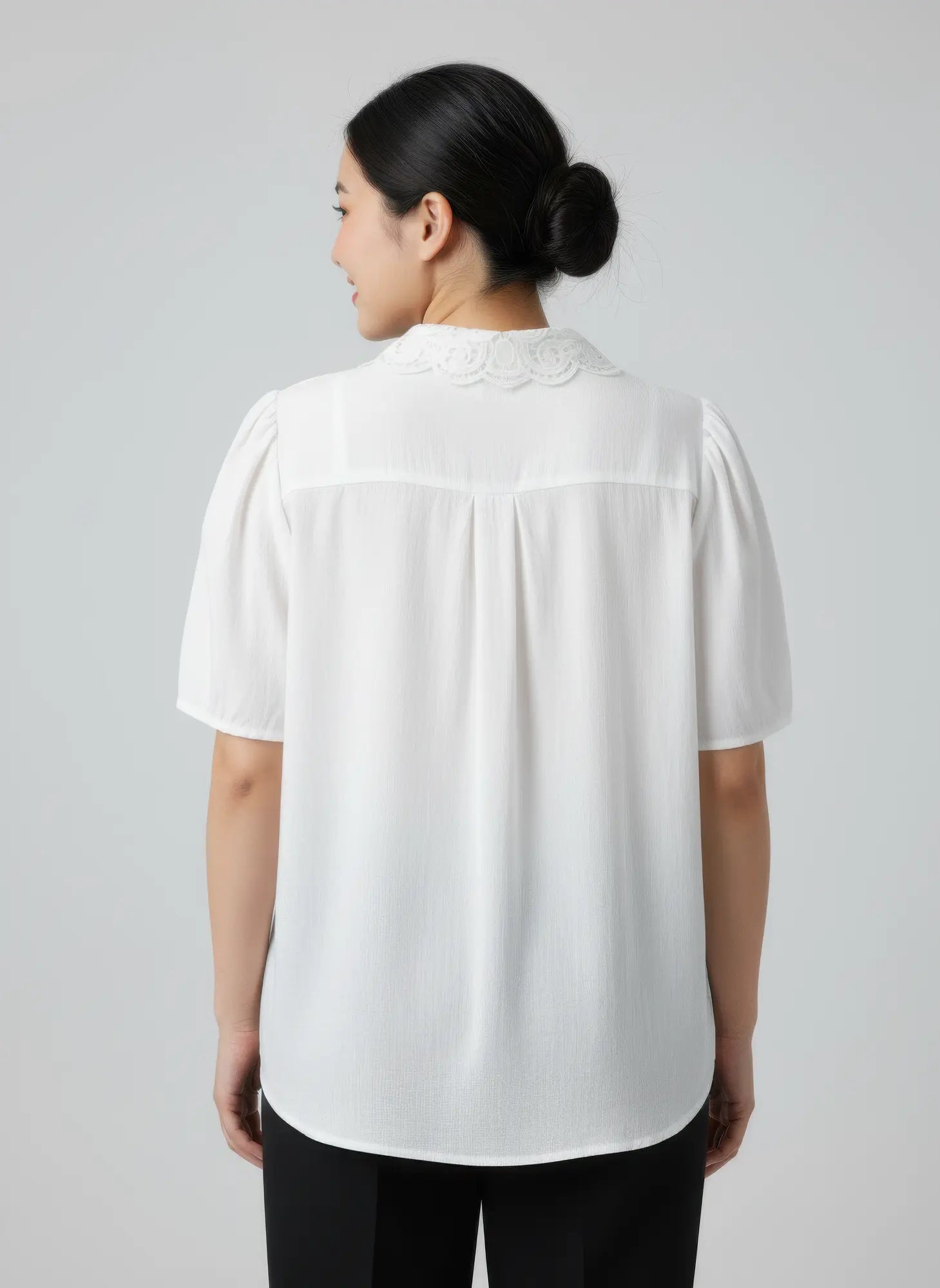 Person wearing a white blouse with a plain background