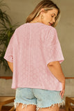 Woman wearing a pink textured top and denim shorts indoors.