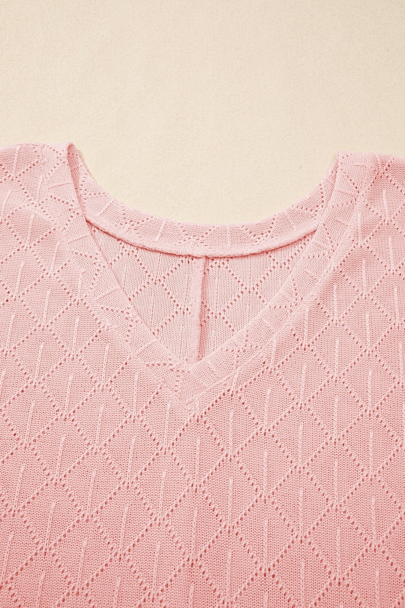 Close-up of a pink textured fabric with a subtle pattern on a beige background