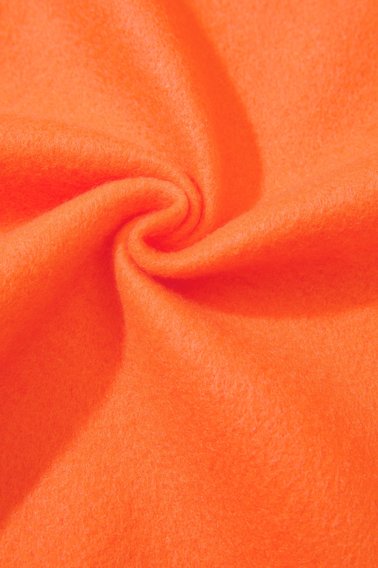 A close-up of bright orange fabric with a soft, slightly fuzzy texture, arranged in a spiral drape pattern.