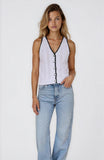 Woman wearing a white sleeveless top with black details and light blue jeans on a white background