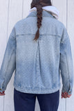 Person viewed from behind wearing a light blue polka-dot denim jacket over a white hoodie and navy pants.