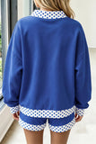A person shown from the back wearing a royal blue sweatshirt and matching shorts set, both featuring white collar and hem details with blue polka dots.