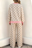 A person shown from the back wearing a beige and white polka dot lounge set with pink trim, standing against a plain off-white wall.
