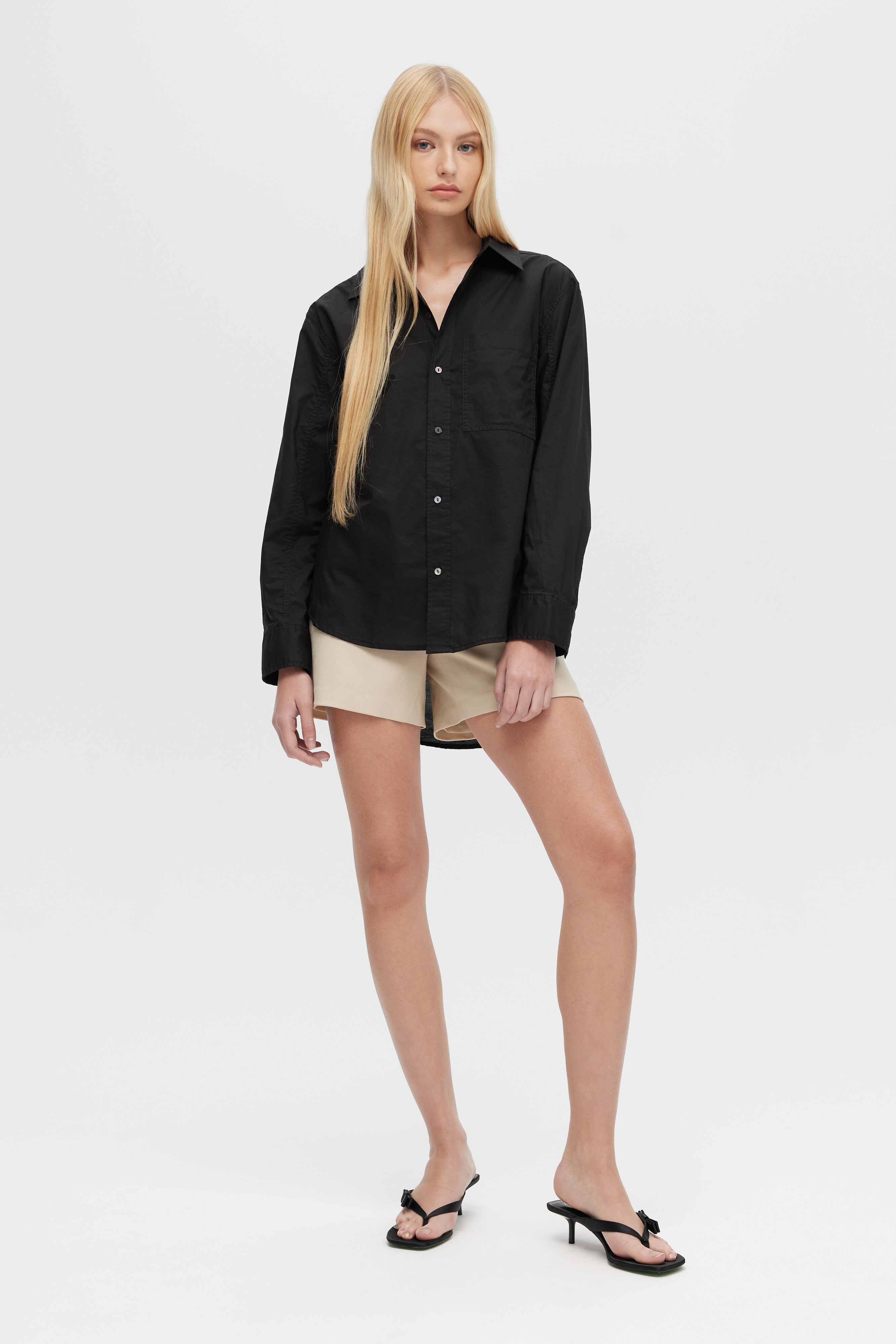 Woman wearing a black shirt and beige shorts on a white background