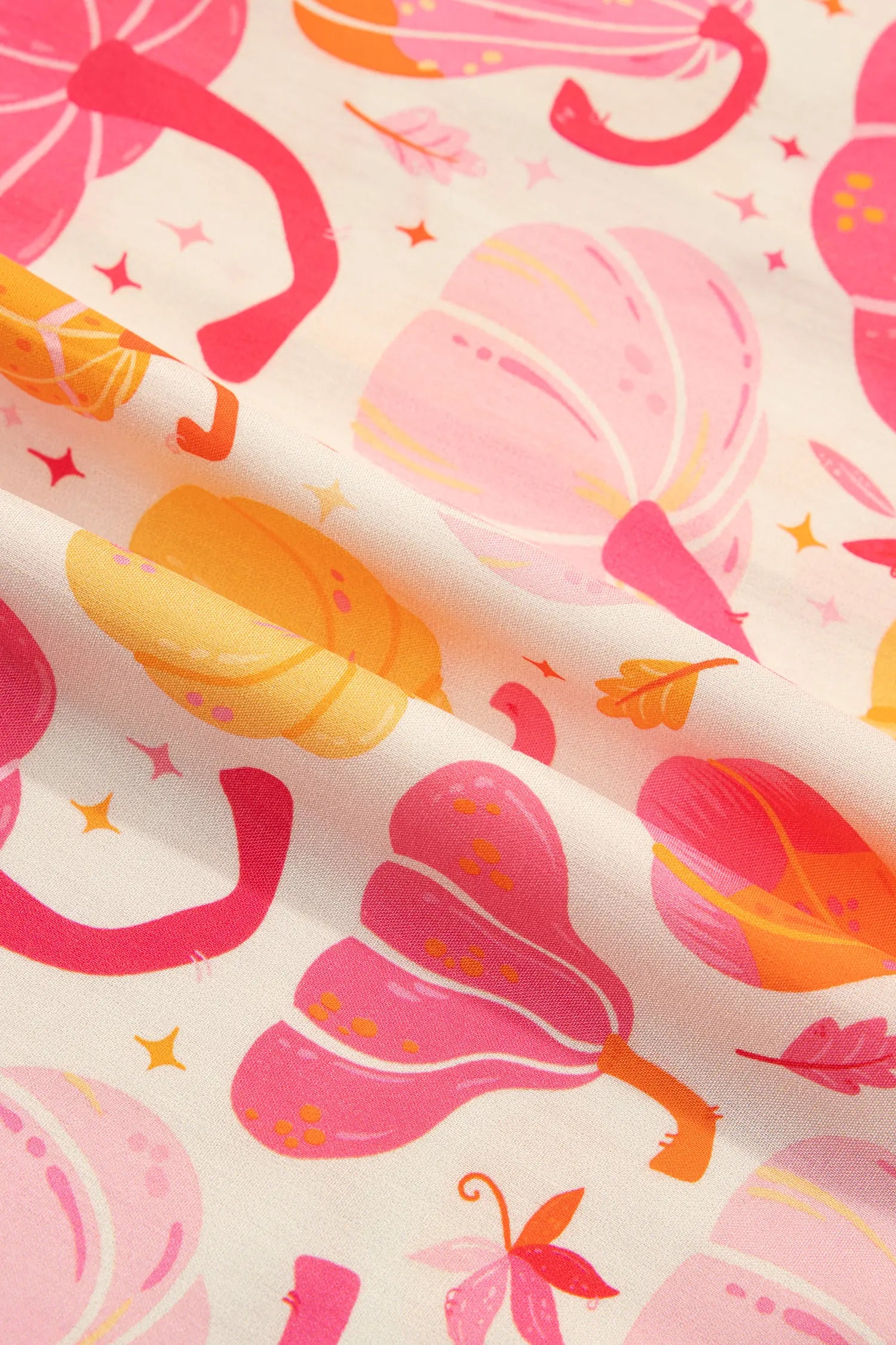 A close-up of a fabric with a colorful autumn pattern featuring pink and orange pumpkins, leaves, and stars on a cream background.