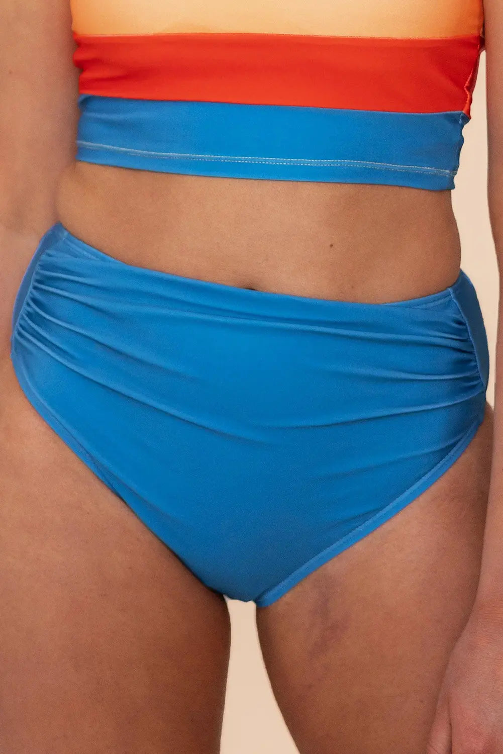 Person wearing a red and blue two-piece swimsuit on a beige background