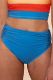 Person wearing a red and blue two-piece swimsuit on a beige background