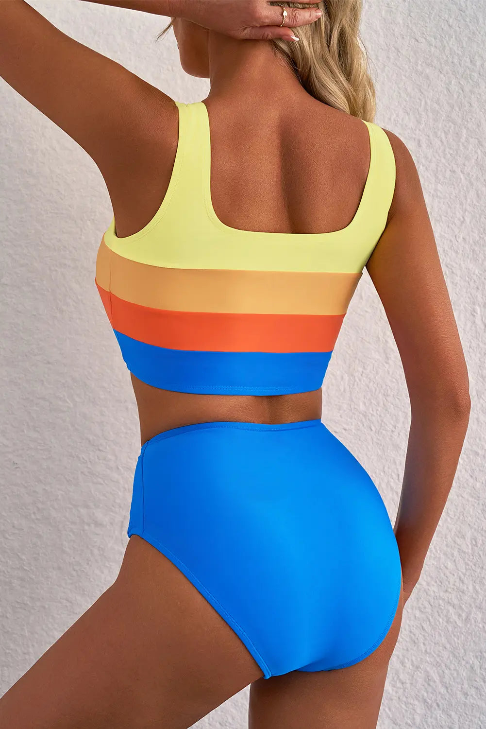 Woman wearing a colorful bikini with a rainbow top and blue bottom on a white background