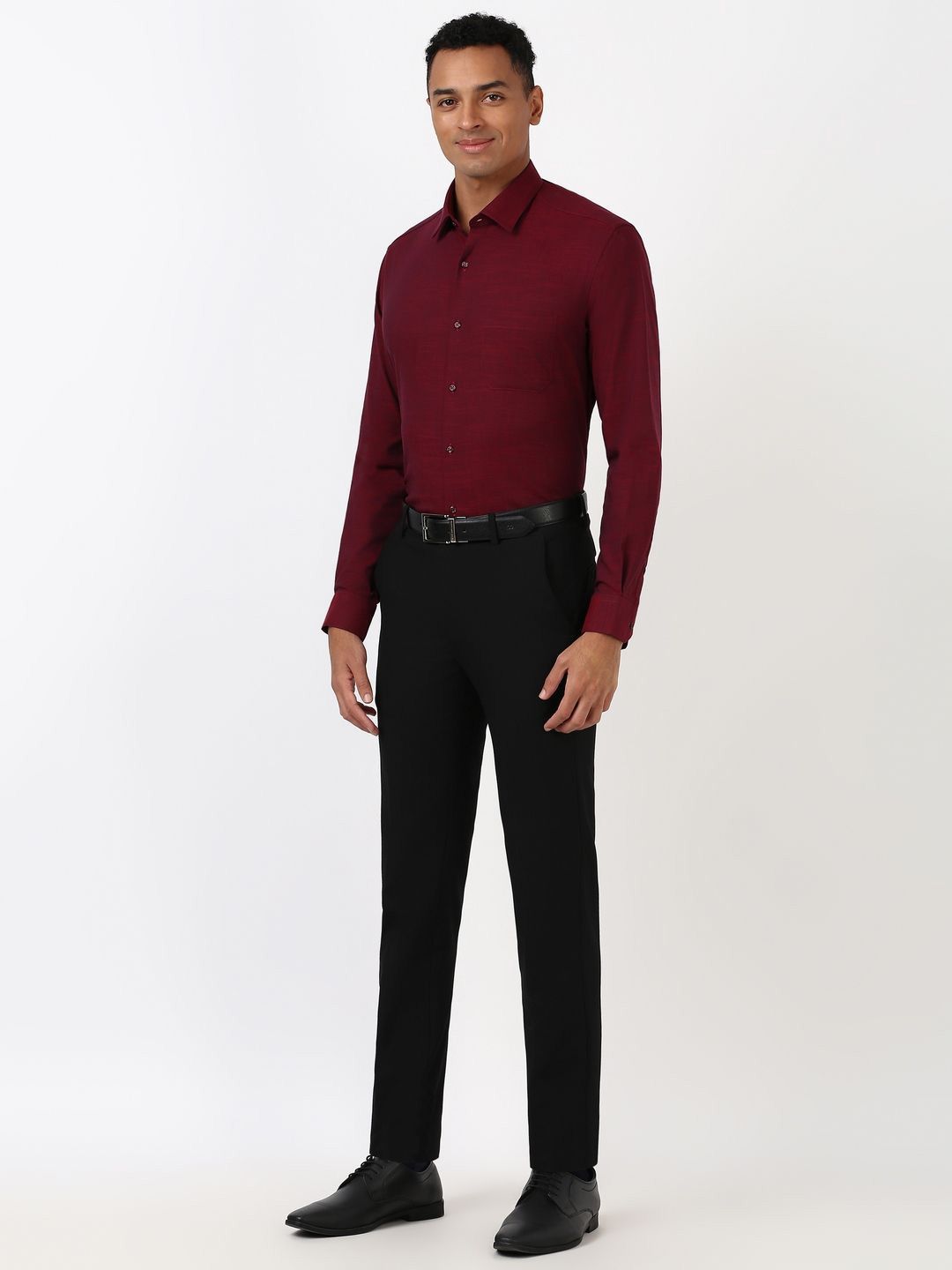 Man wearing a burgundy dress shirt and black pants on a white background