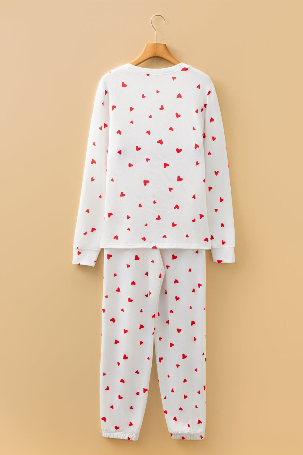 Children's pajama set with red heart patterns on a beige background