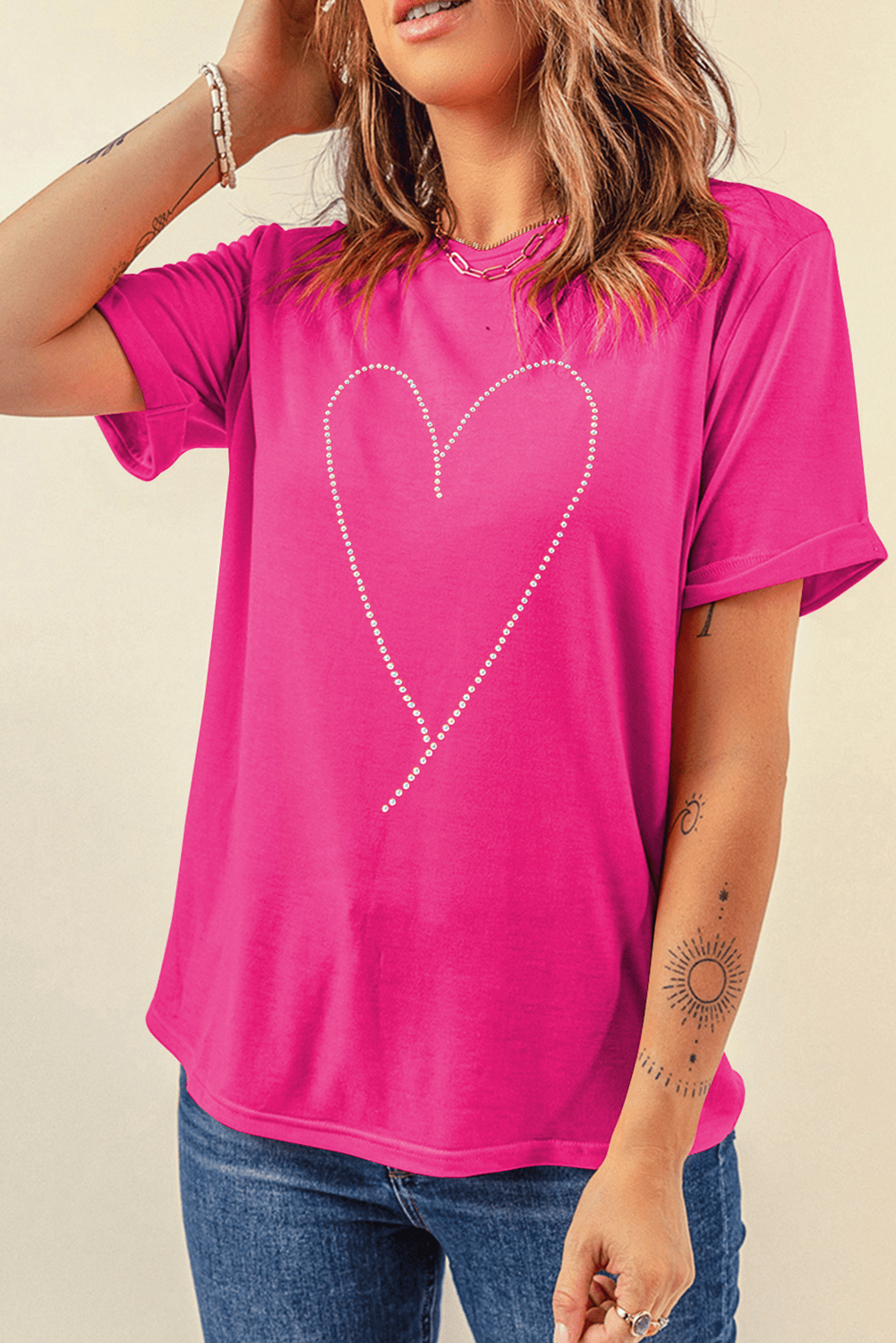 Person wearing a bright pink t-shirt with a heart design on a beige background