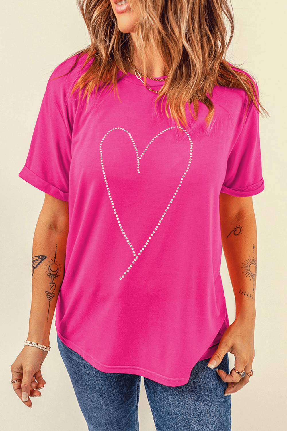 Person wearing a bright pink t-shirt with a heart design on a beige background