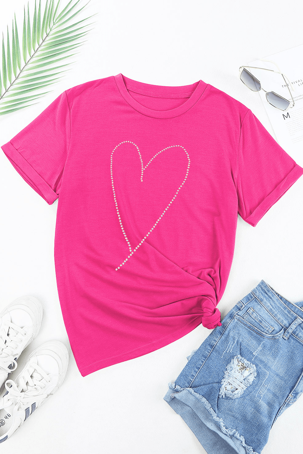 Pink t-shirt with a heart design, sunglasses, and white sneakers on a white background