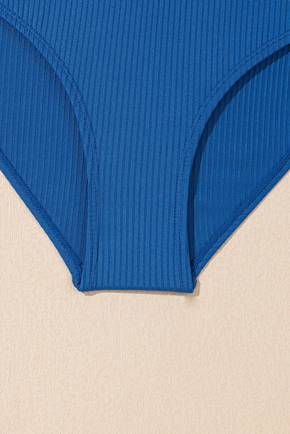Blue ribbed swimsuit bottom on a beige background