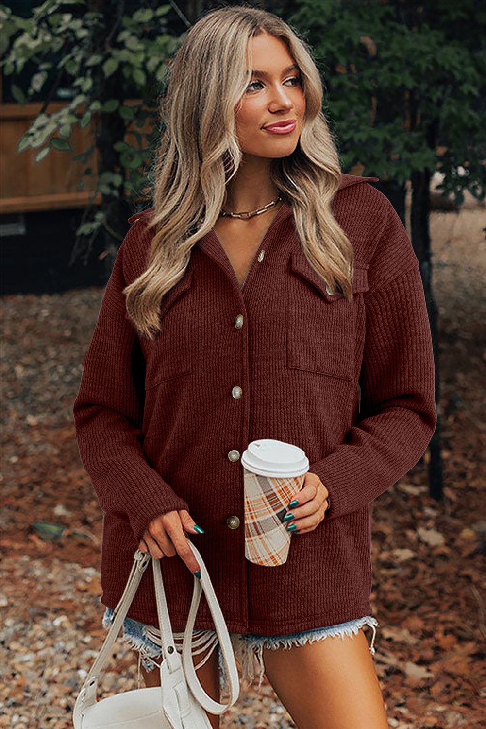Woman in a brown cardigan holding a coffee cup outdoors