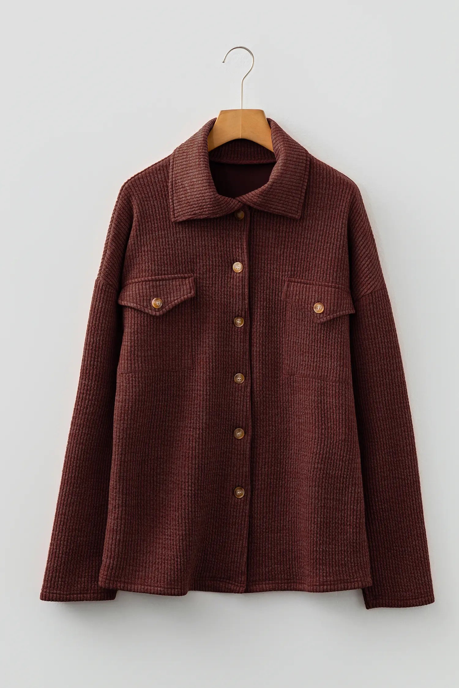 Brown corduroy jacket on a wooden hanger against a white background
