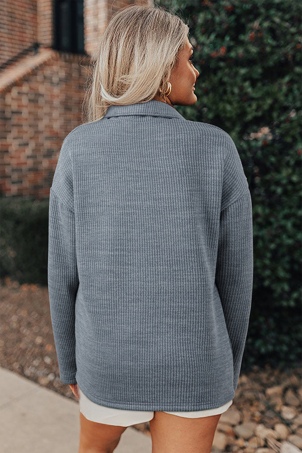 Woman wearing a gray textured sweater in an outdoor setting.