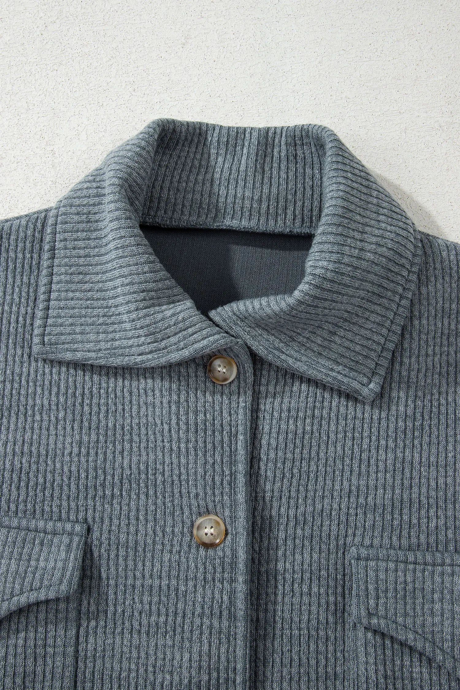 Close-up of a textured gray jacket with buttons on a light gray background