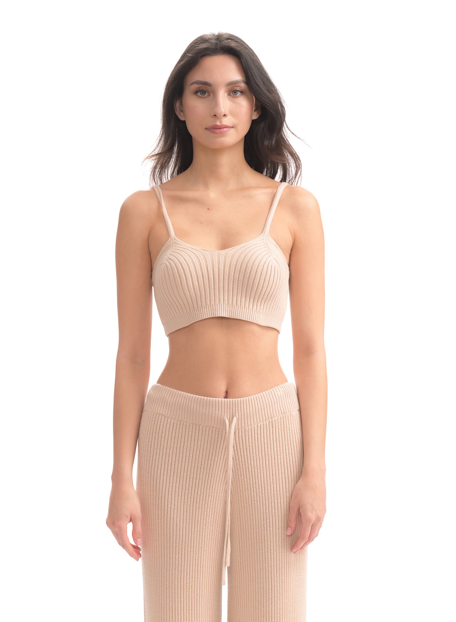 Woman wearing a beige ribbed crop top and pants on a white background