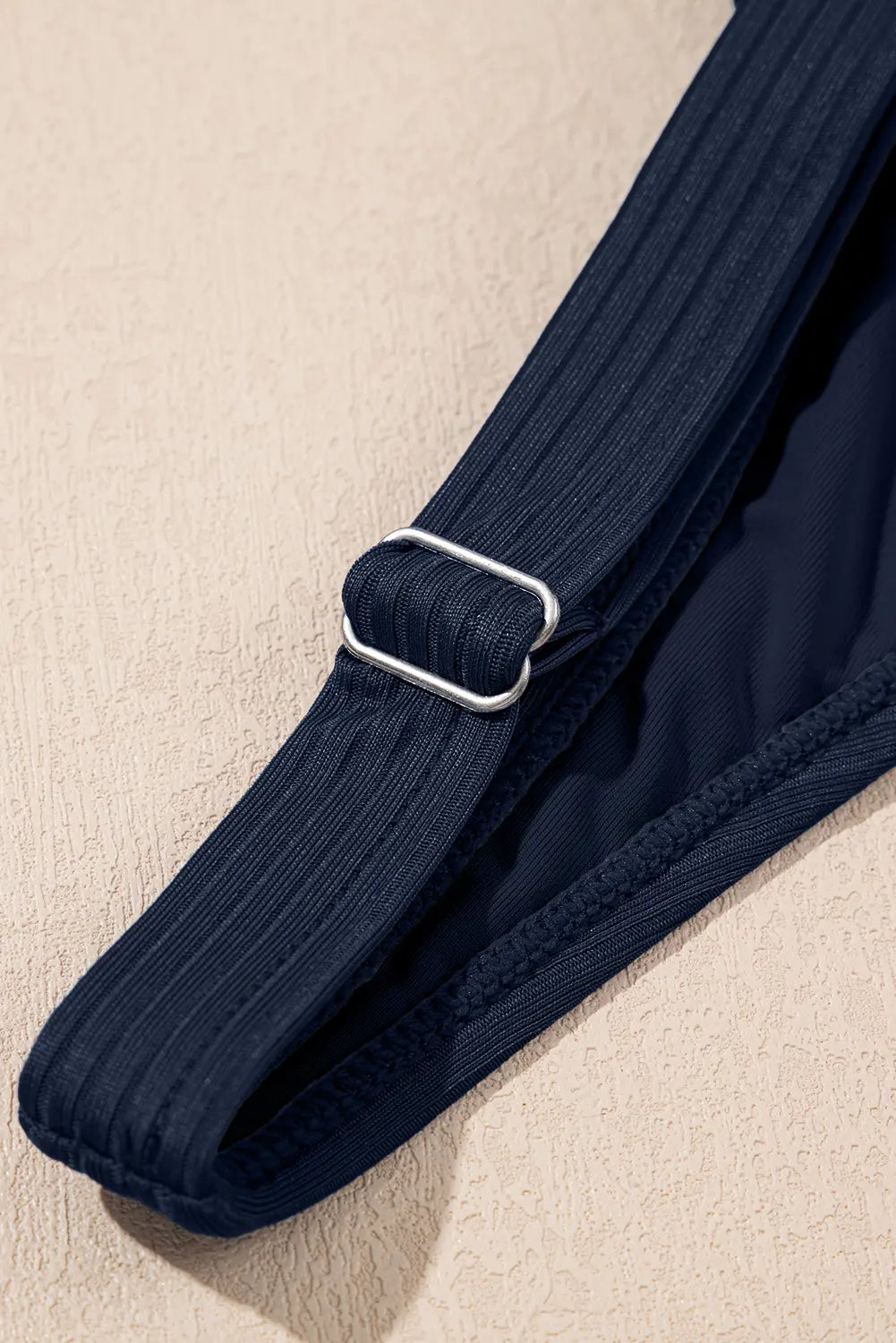 Navy blue belt with a silver buckle on a beige background