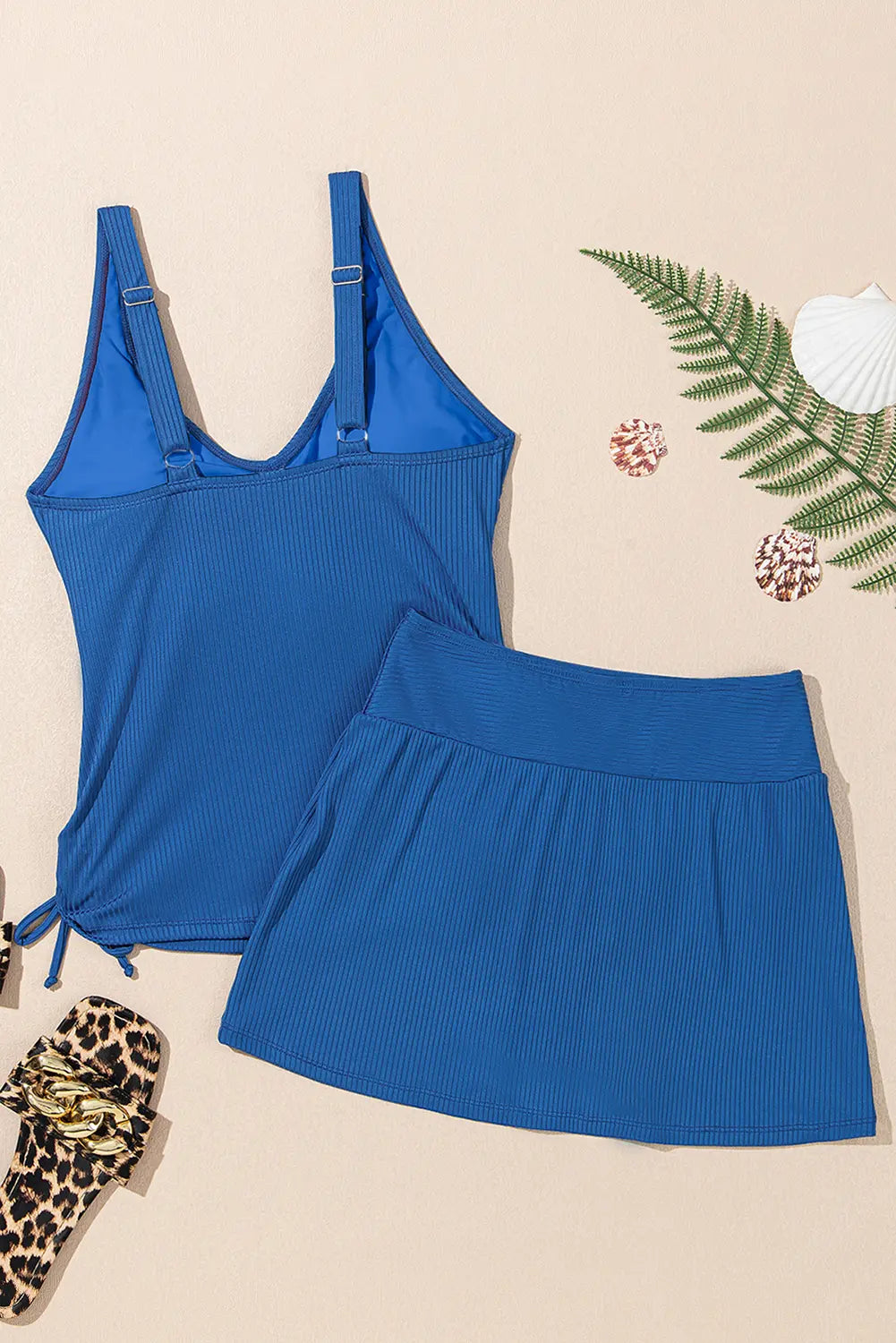 Blue tank top and skirt set on a beige background with decorative elements.