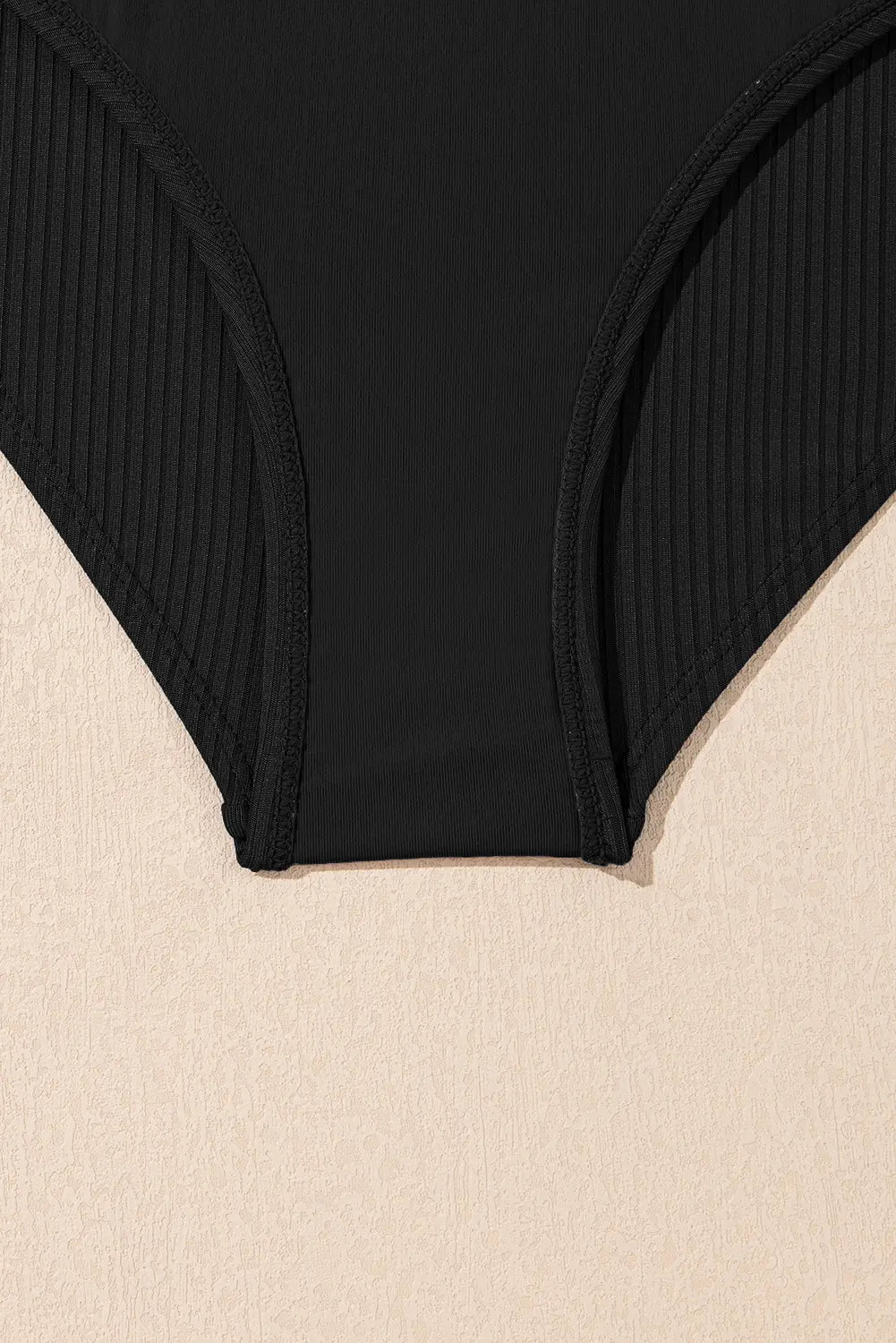 Black ribbed bikini bottom on a beige background