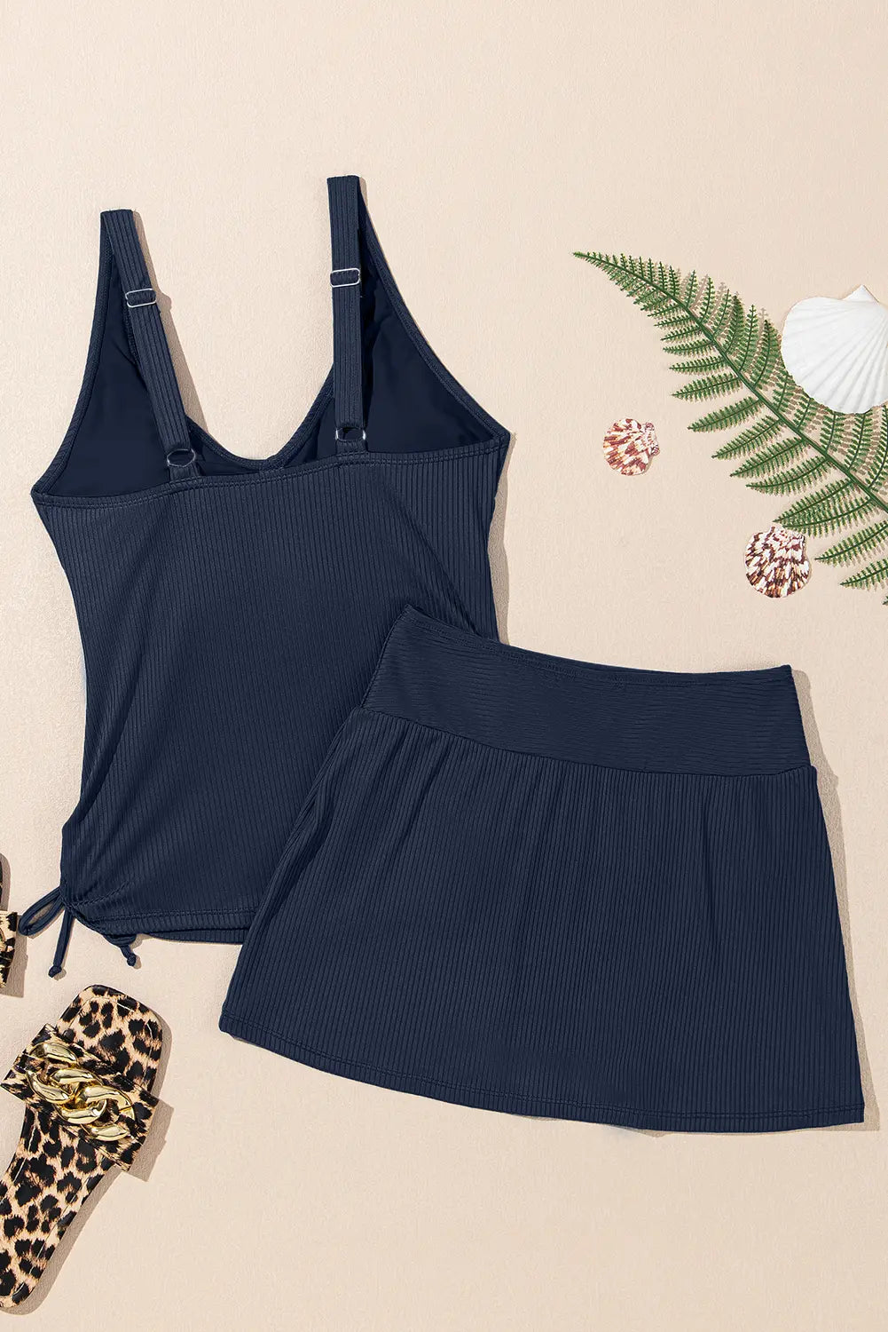 Navy blue tank top and skirt set on a beige background with decorative elements.