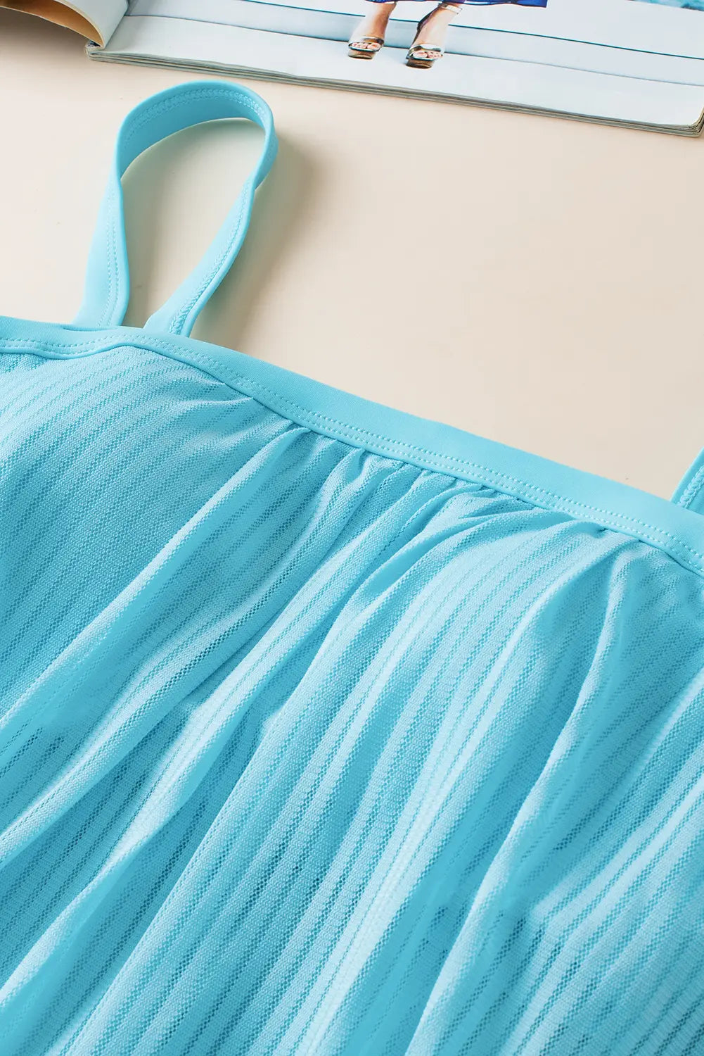 Close-up of a blue mesh fabric with straps on a beige surface.
