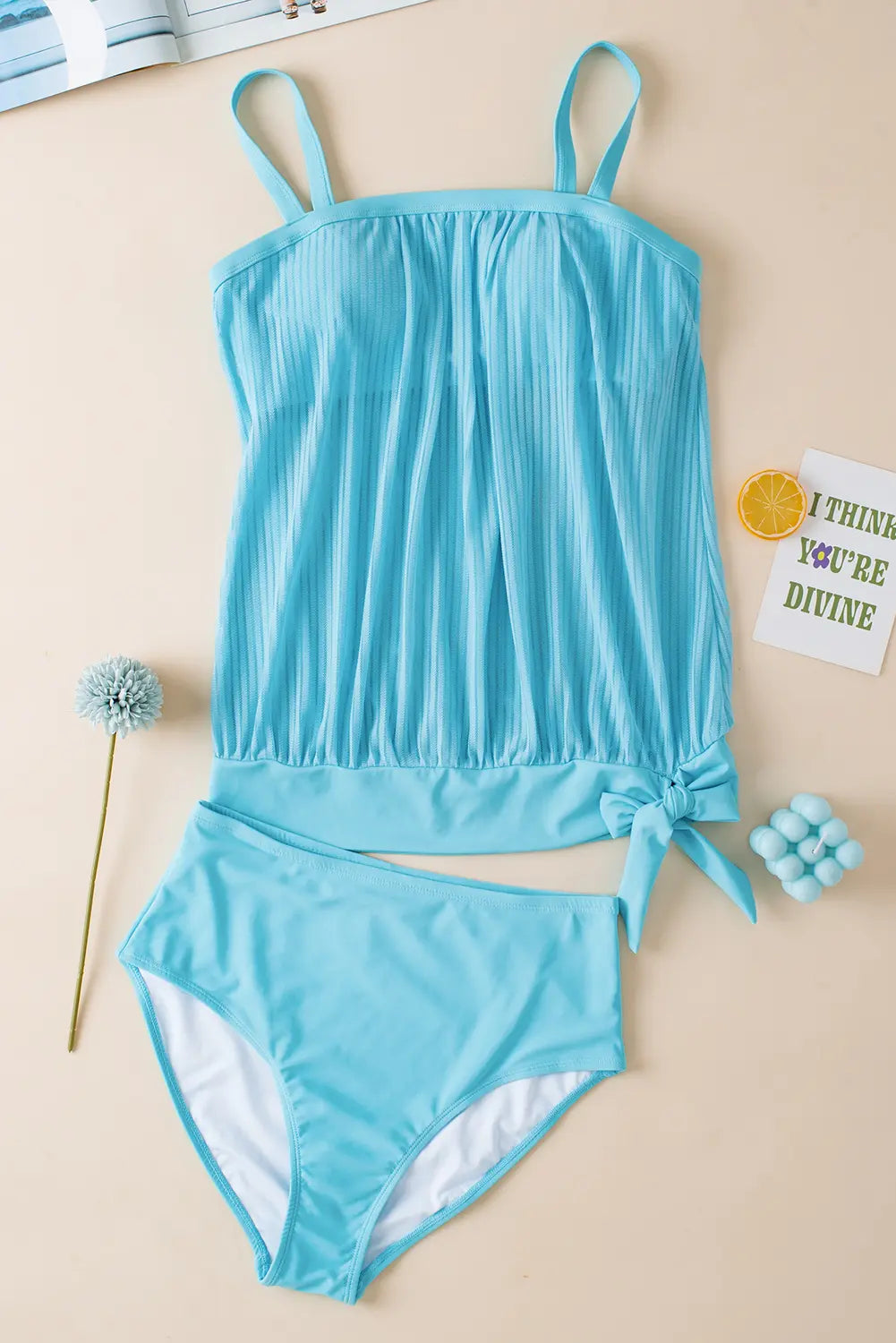 Blue swimsuit set on a beige surface with decorative items.