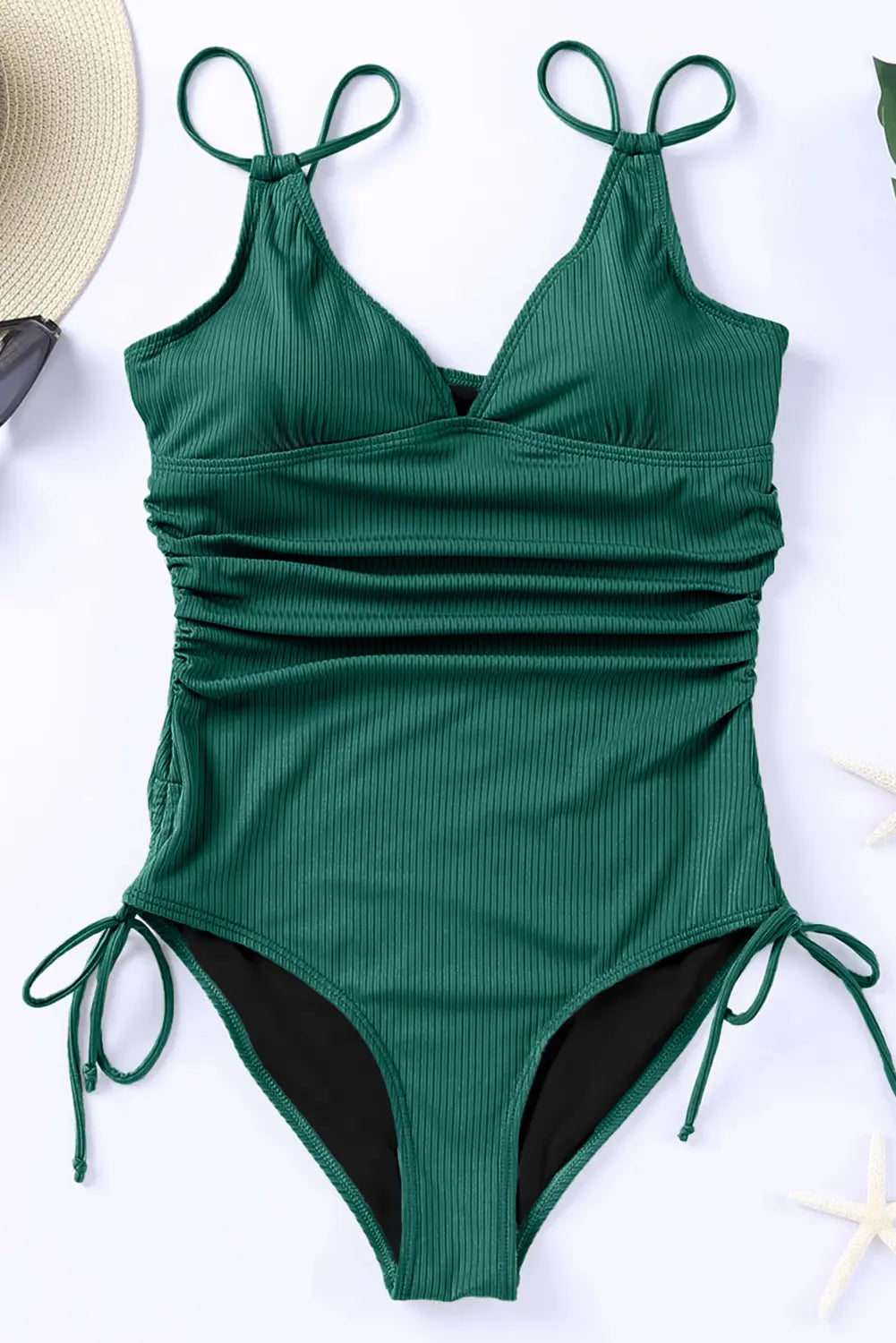Green ribbed swimsuit with tie straps on a white surface