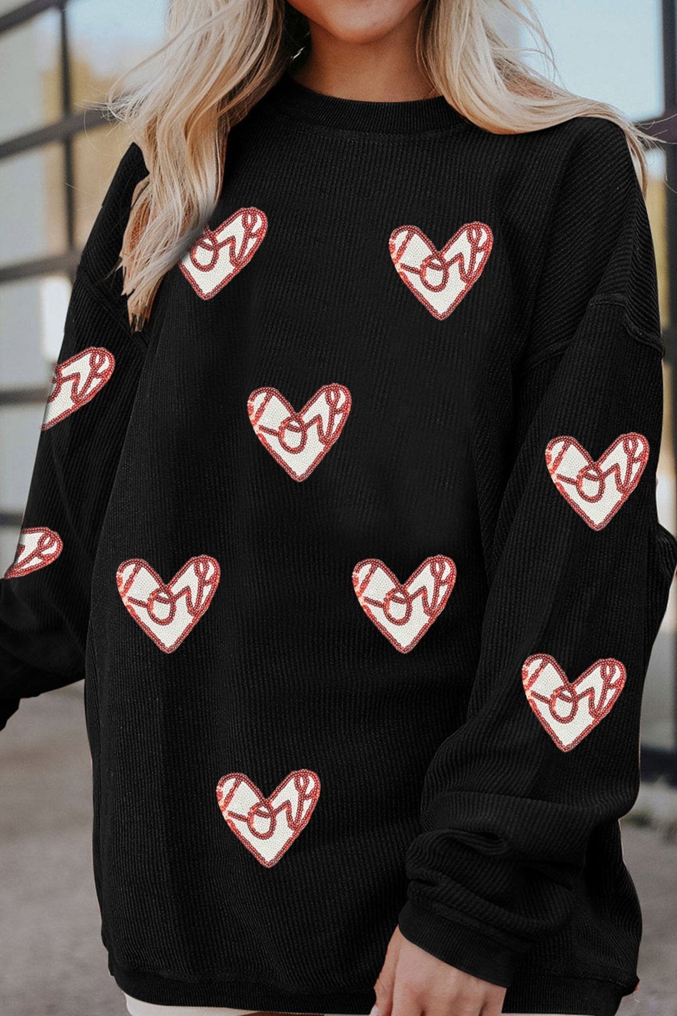 Black sweater with red heart patterns worn by a person