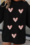Black sweater with red heart designs on a blurred background