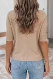 Person wearing a beige sweater and blue jeans with a neutral background.