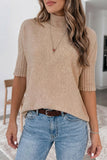 Person wearing a beige sweater and blue jeans indoors.