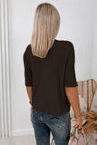 Woman from behind in a dark brown short-sleeve ribbed top, blue jeans, holding a beige bag.