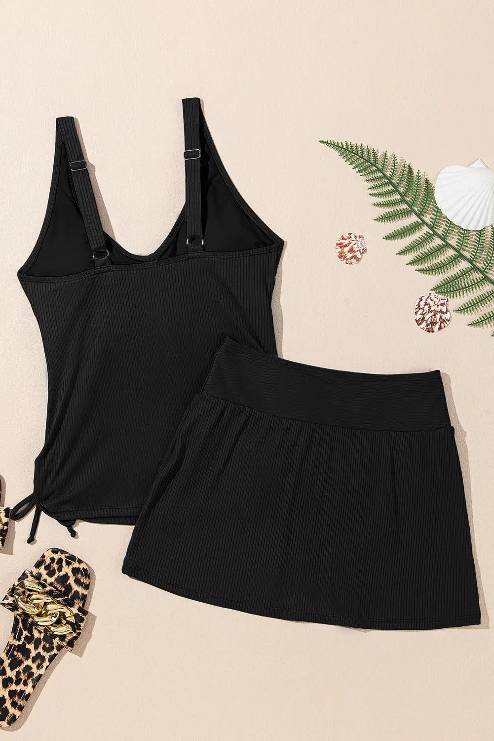 Black dress with straps on a beige background with decorative elements