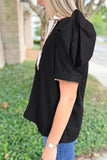 Person wearing a black blouse with a blurred outdoor background
