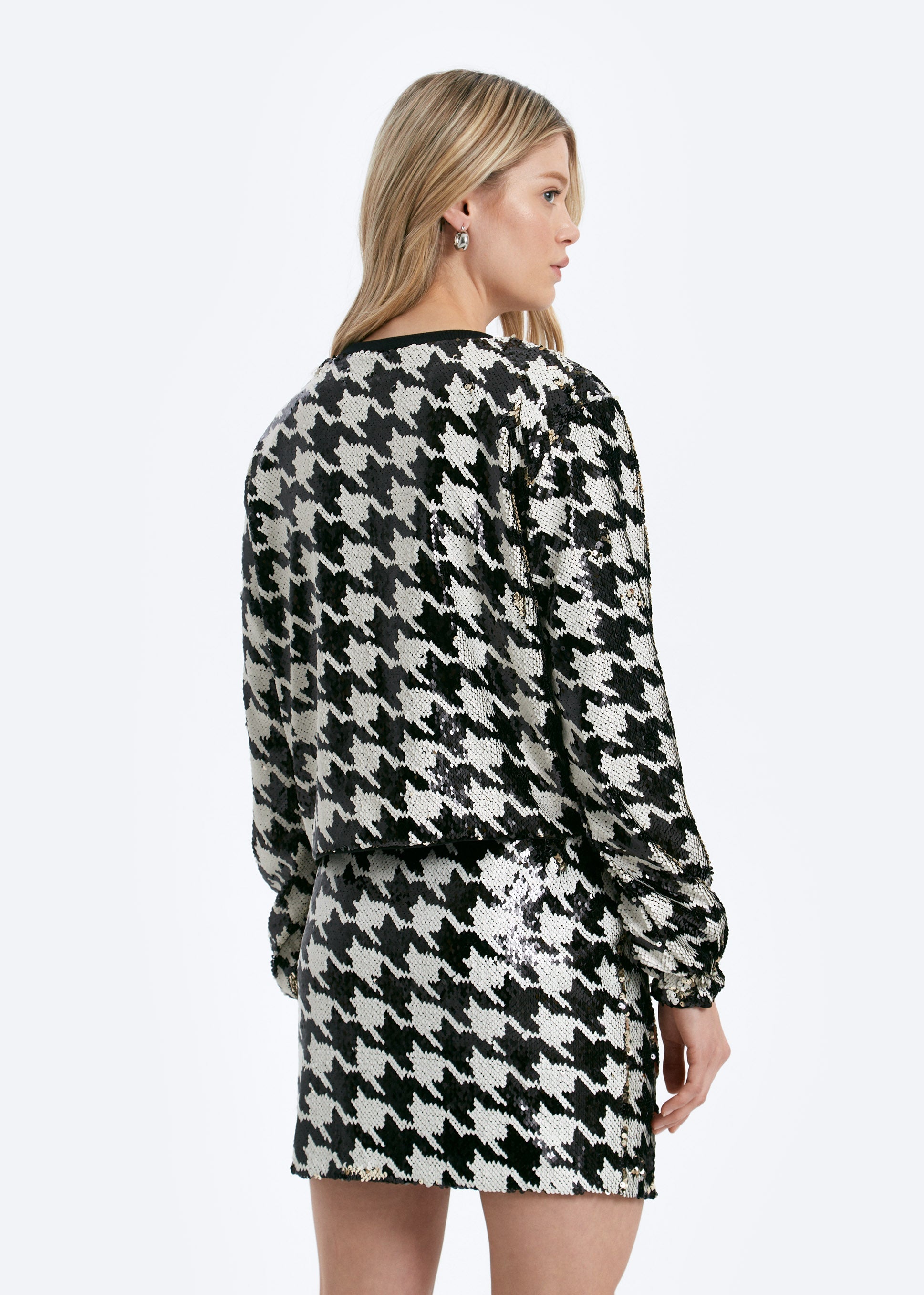 Woman wearing a black and white houndstooth pattern dress on a white background