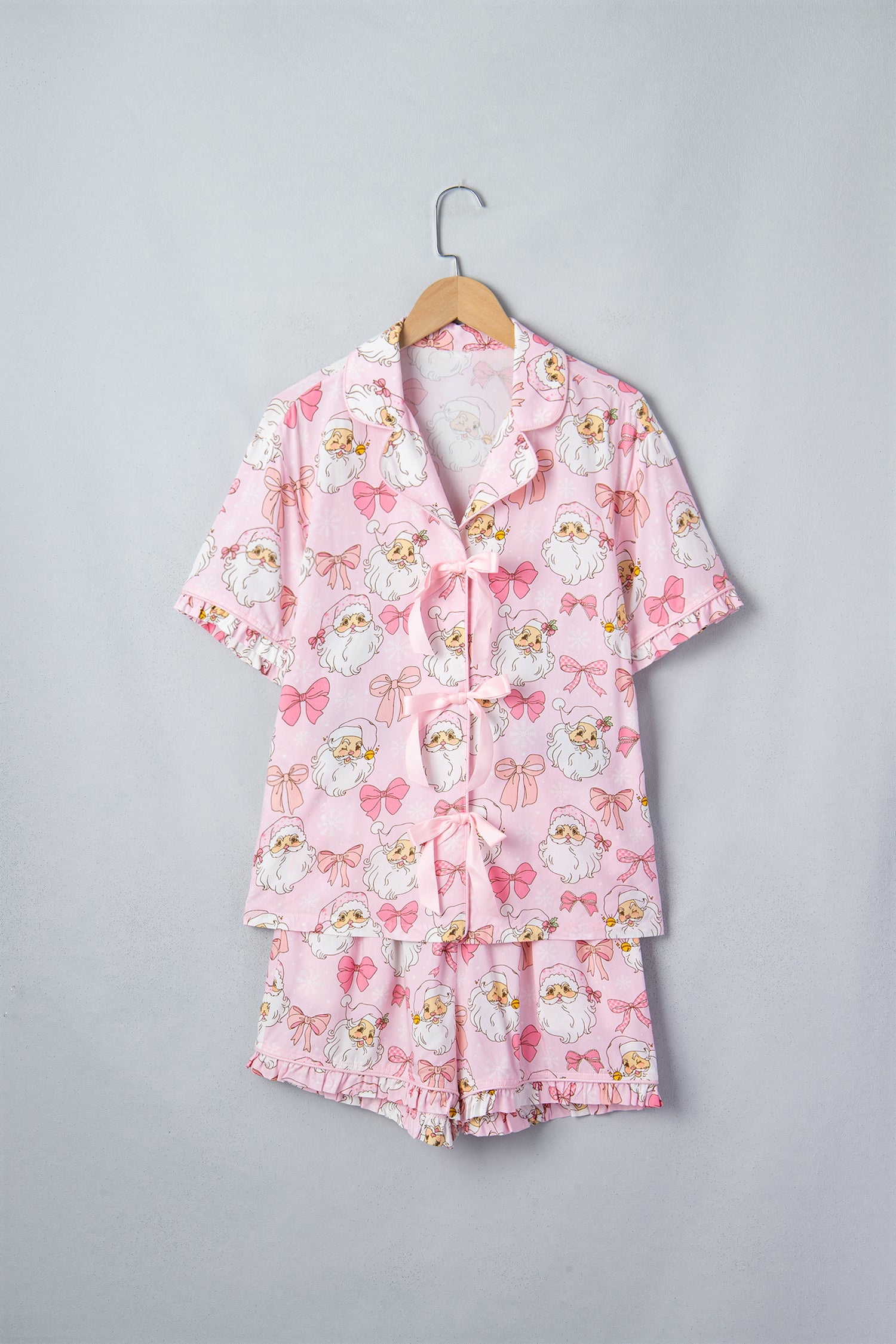 Pink pajama set with cartoon owls and bows on wooden hanger.