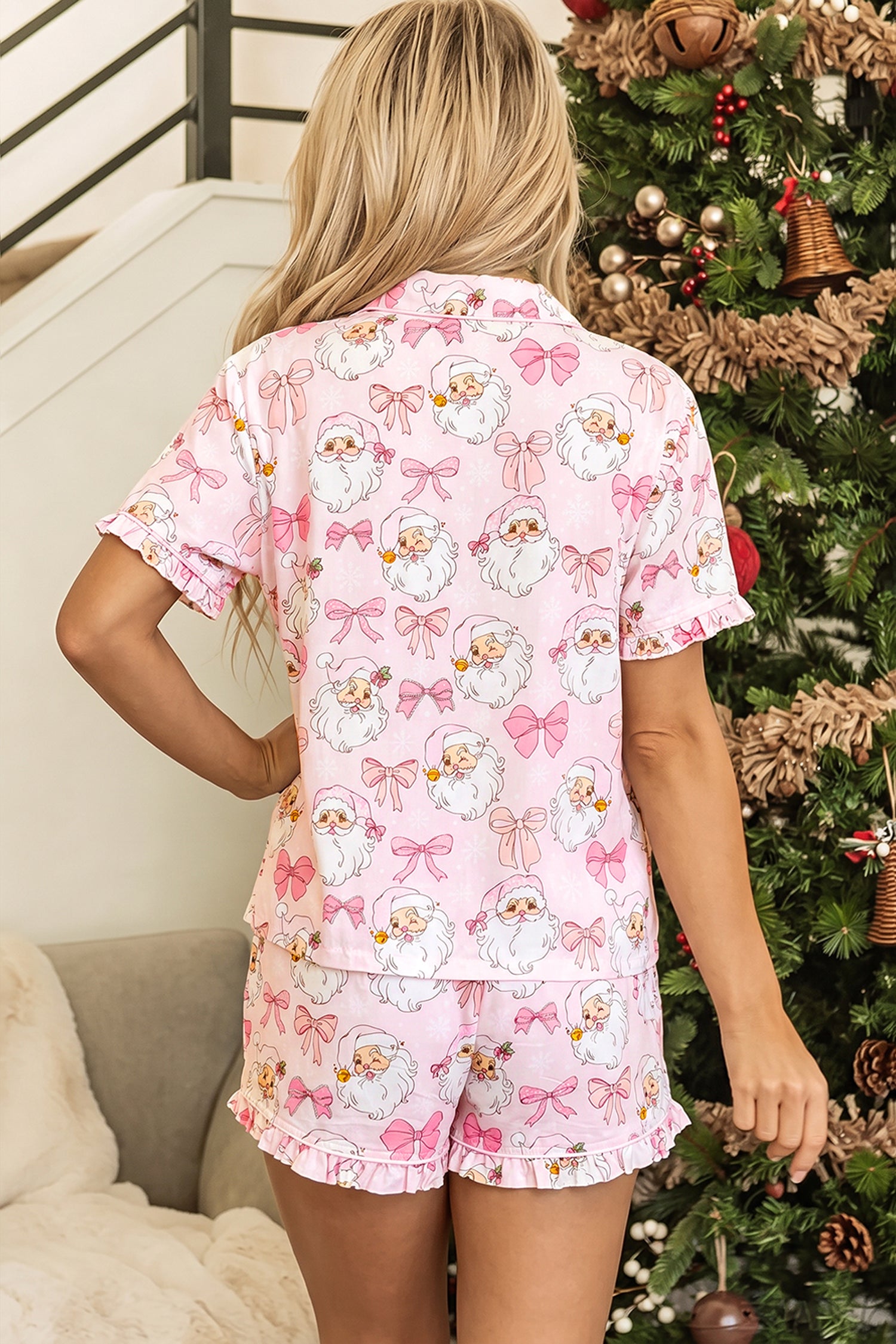 Back view of woman in pink Santa and bow print pajamas.