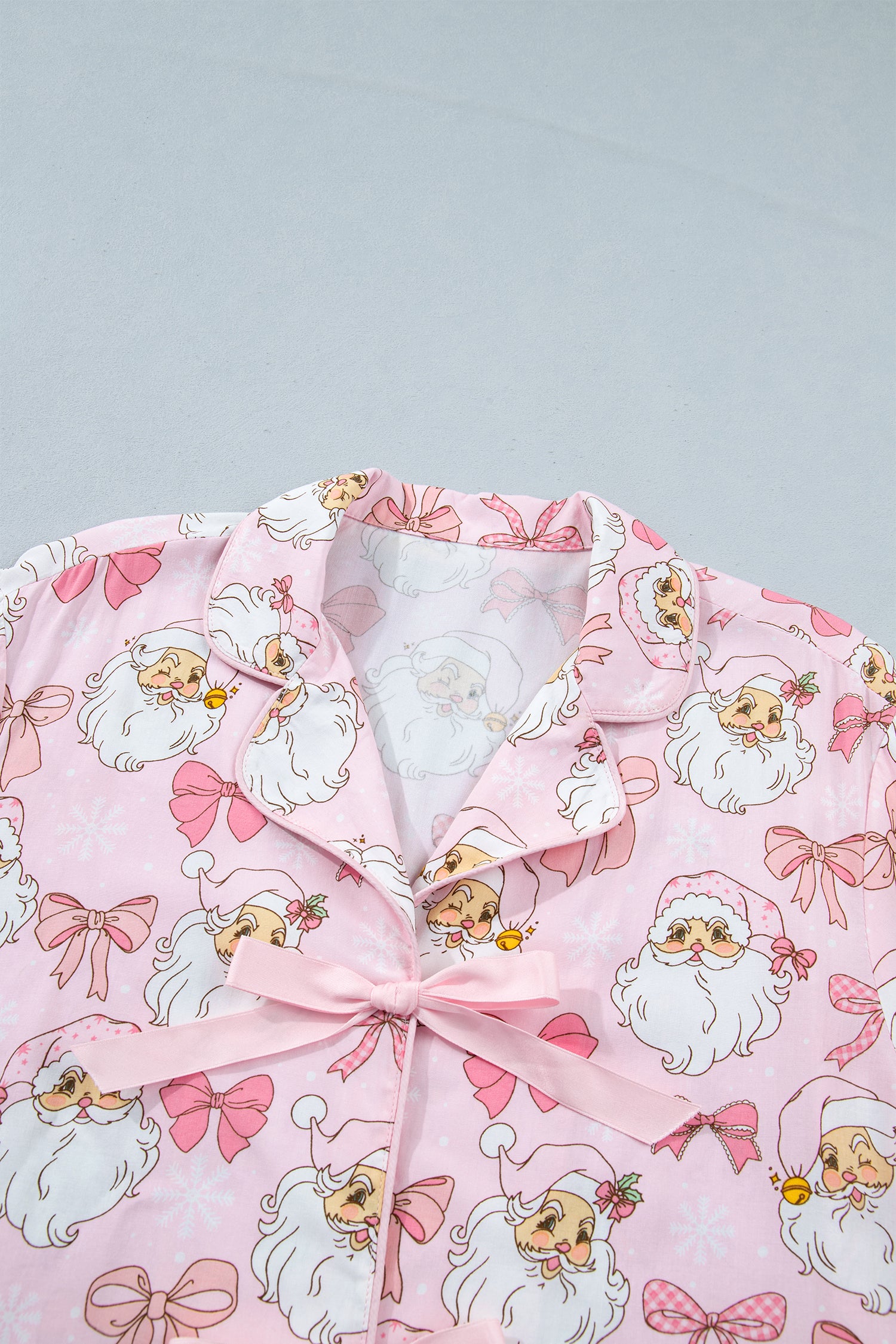 Pink pajama top with Santa print and matching ribbon bow.