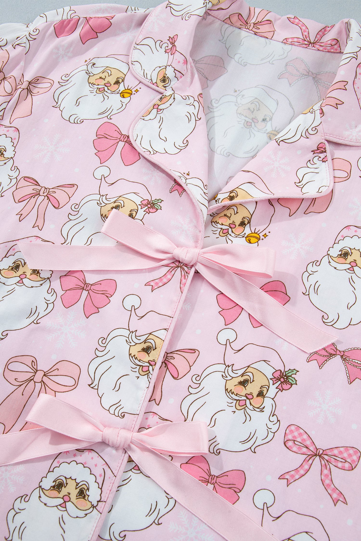 Pink pajama top with Santa and bow print and satin tie closure.