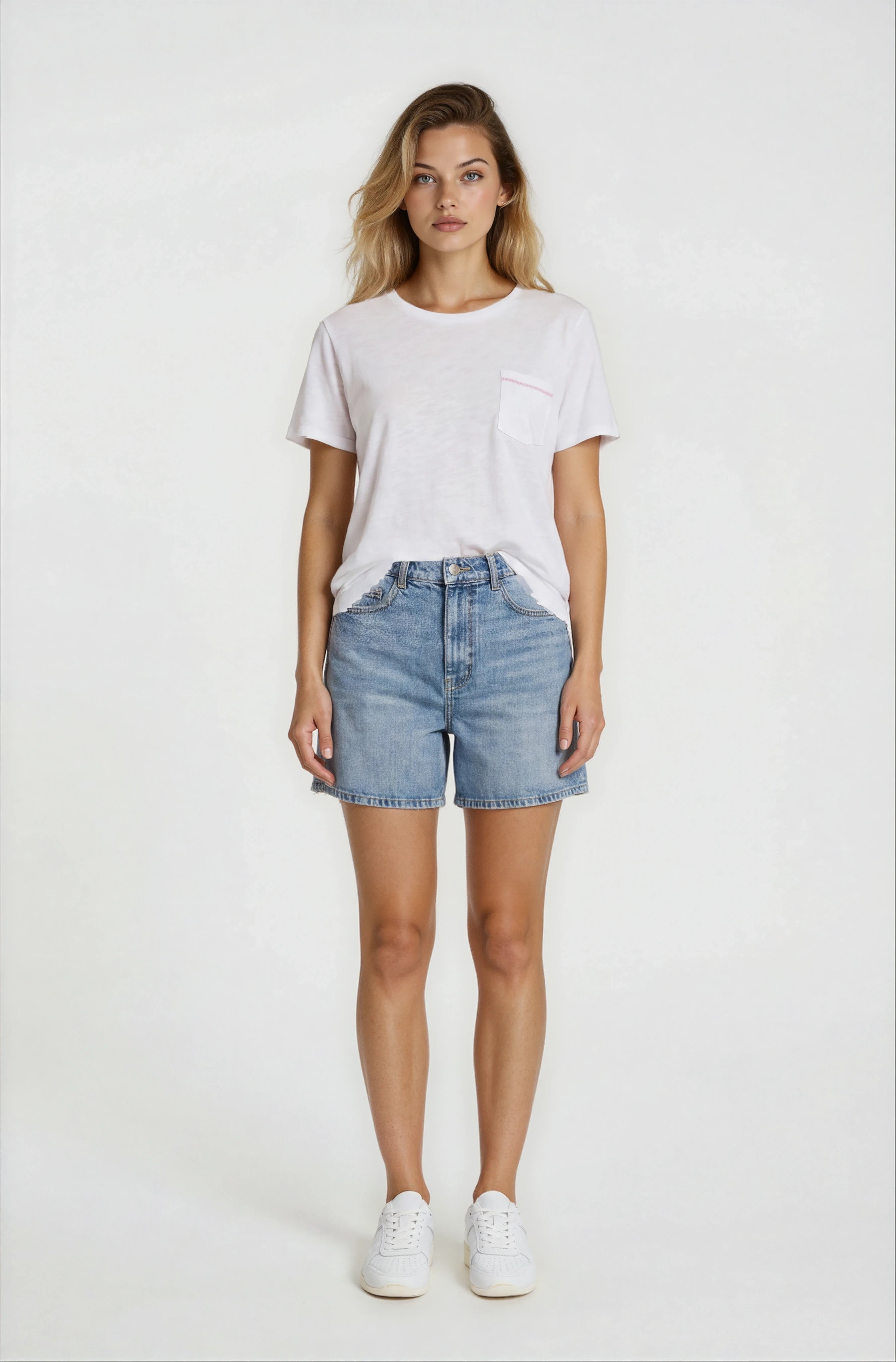 Woman wearing a white t-shirt and denim shorts on a plain background