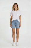 Woman wearing a white t-shirt and denim shorts on a plain background